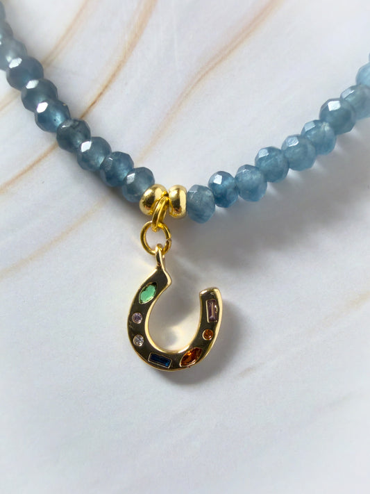 Necklace with blue beads and a gold charm on a light background
