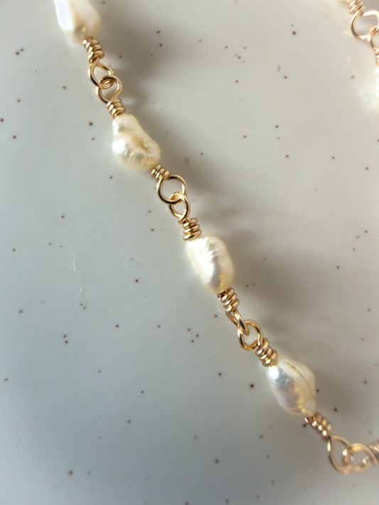 Pearl necklace with gold clasps on a light background