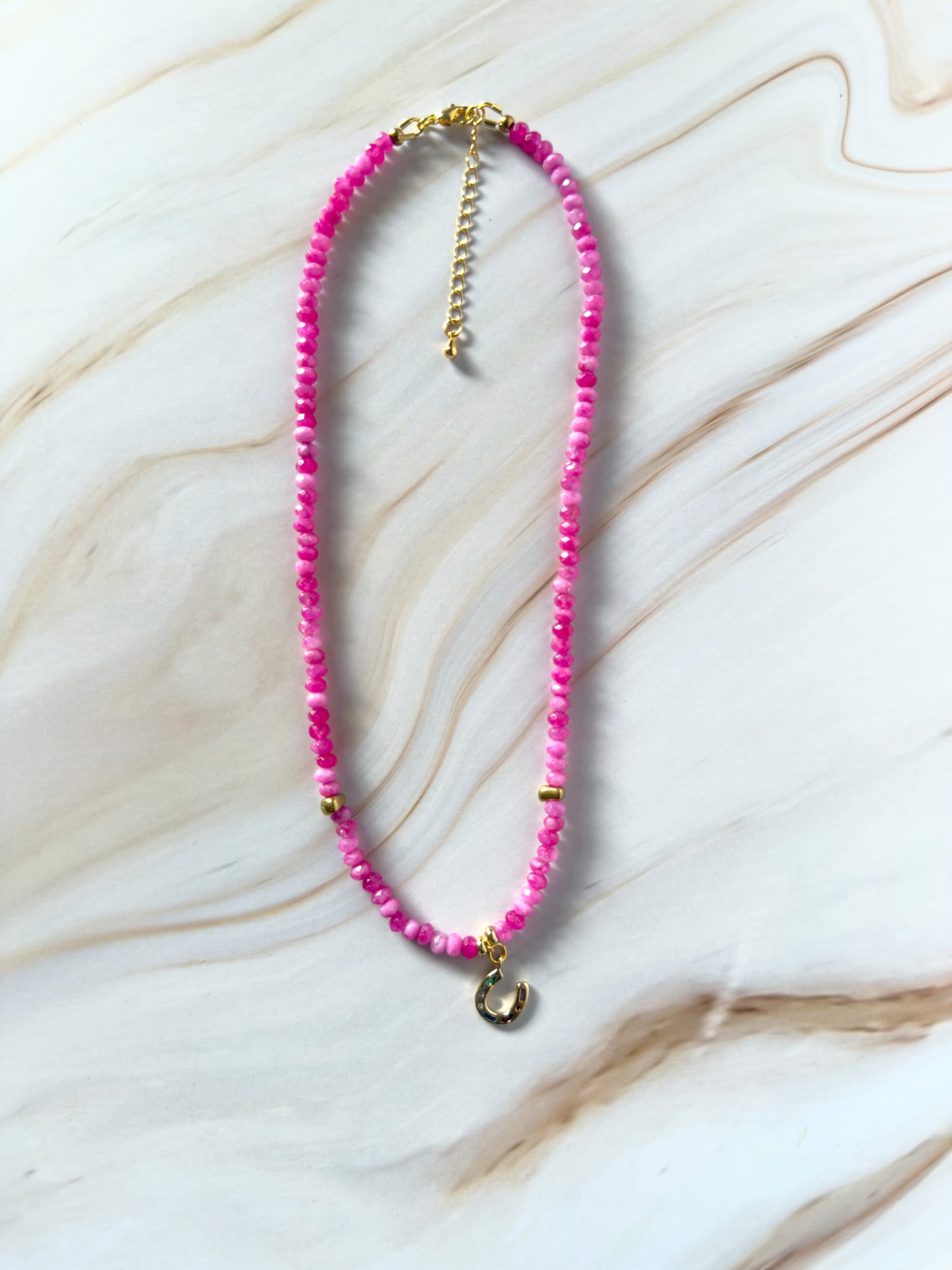 Necklace with pink beads and gold accents on a marble surface