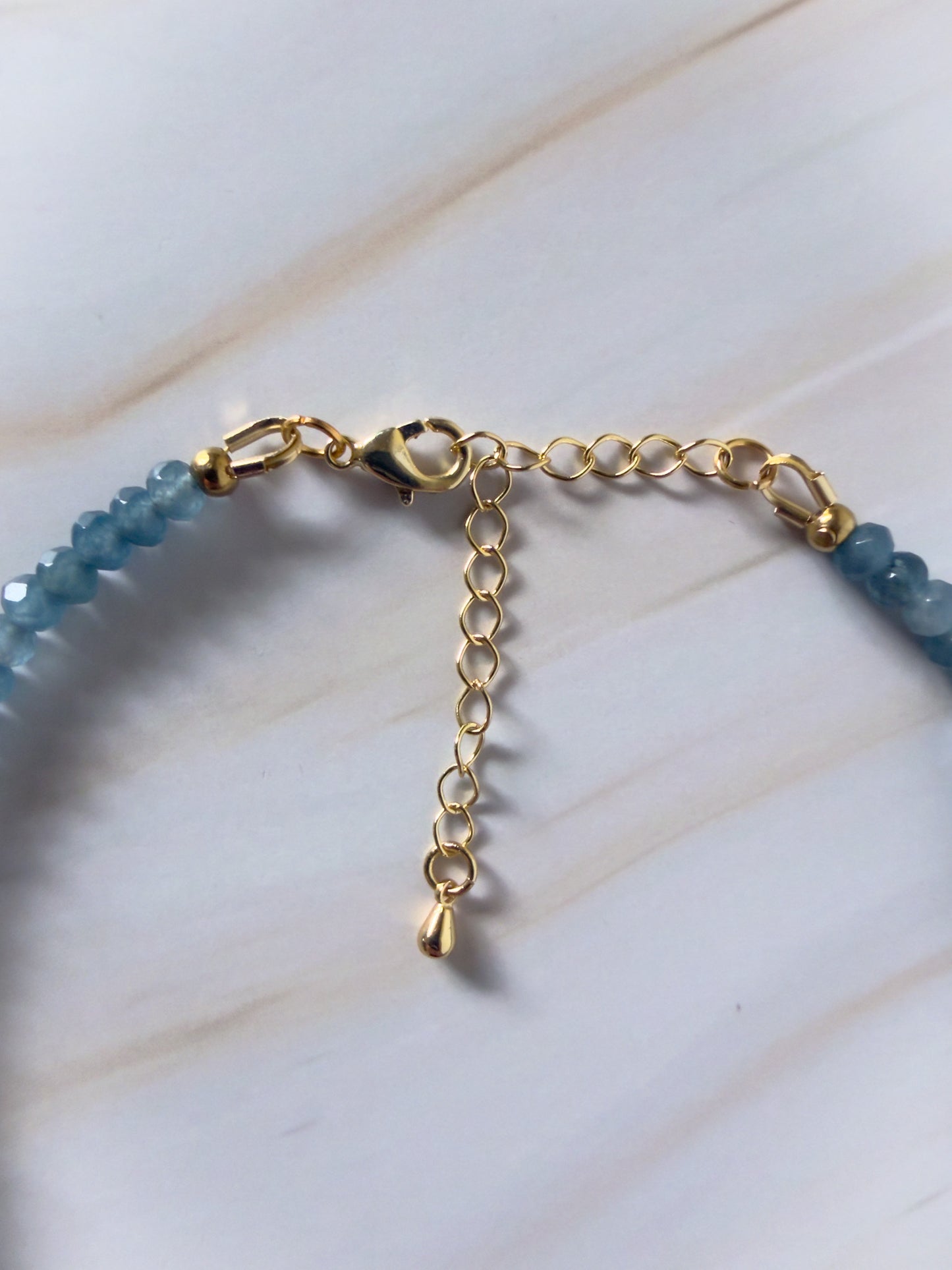 Gold necklace with blue beads on a white background