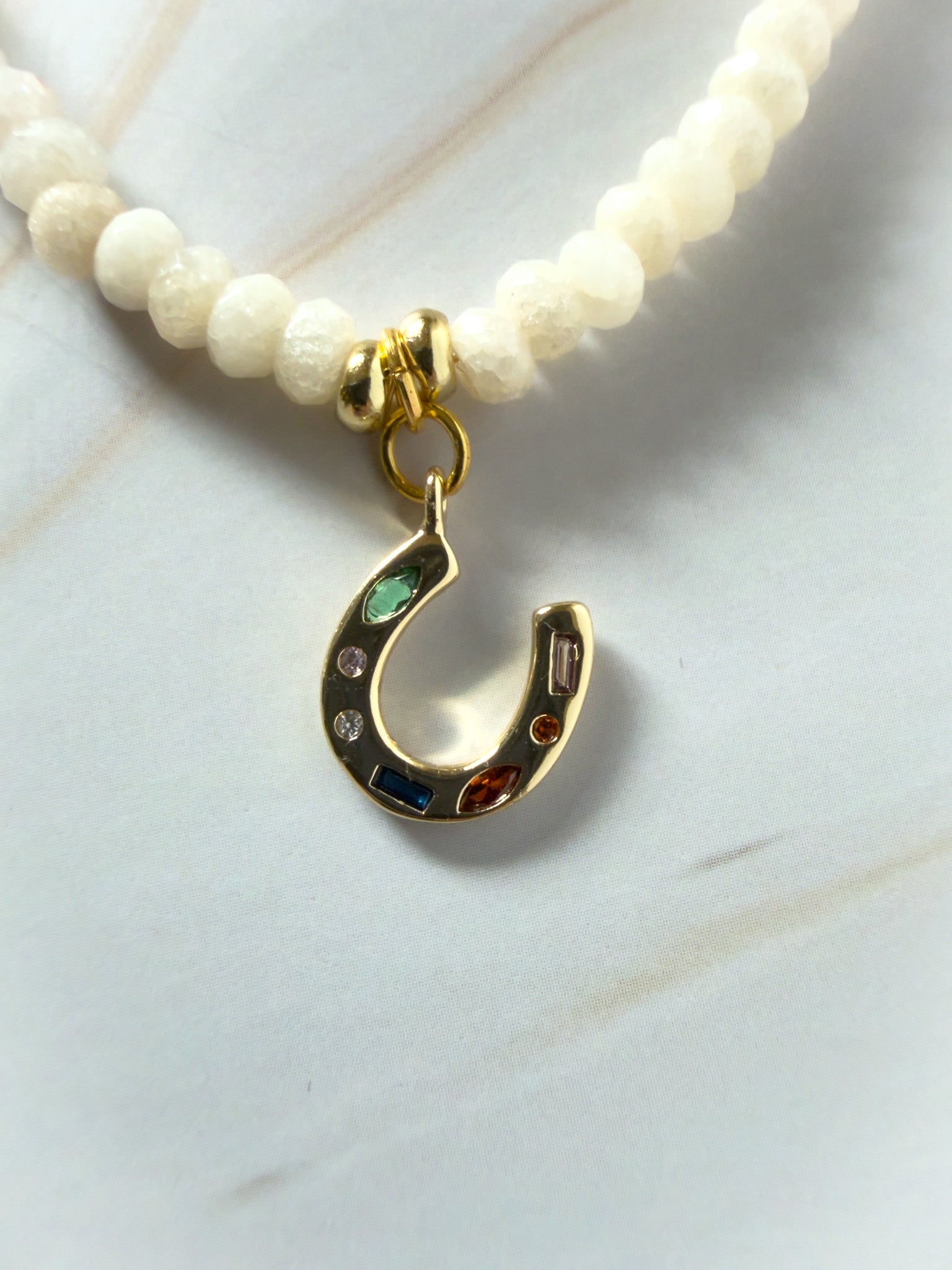 Necklace with a gold horseshoe charm on a white background