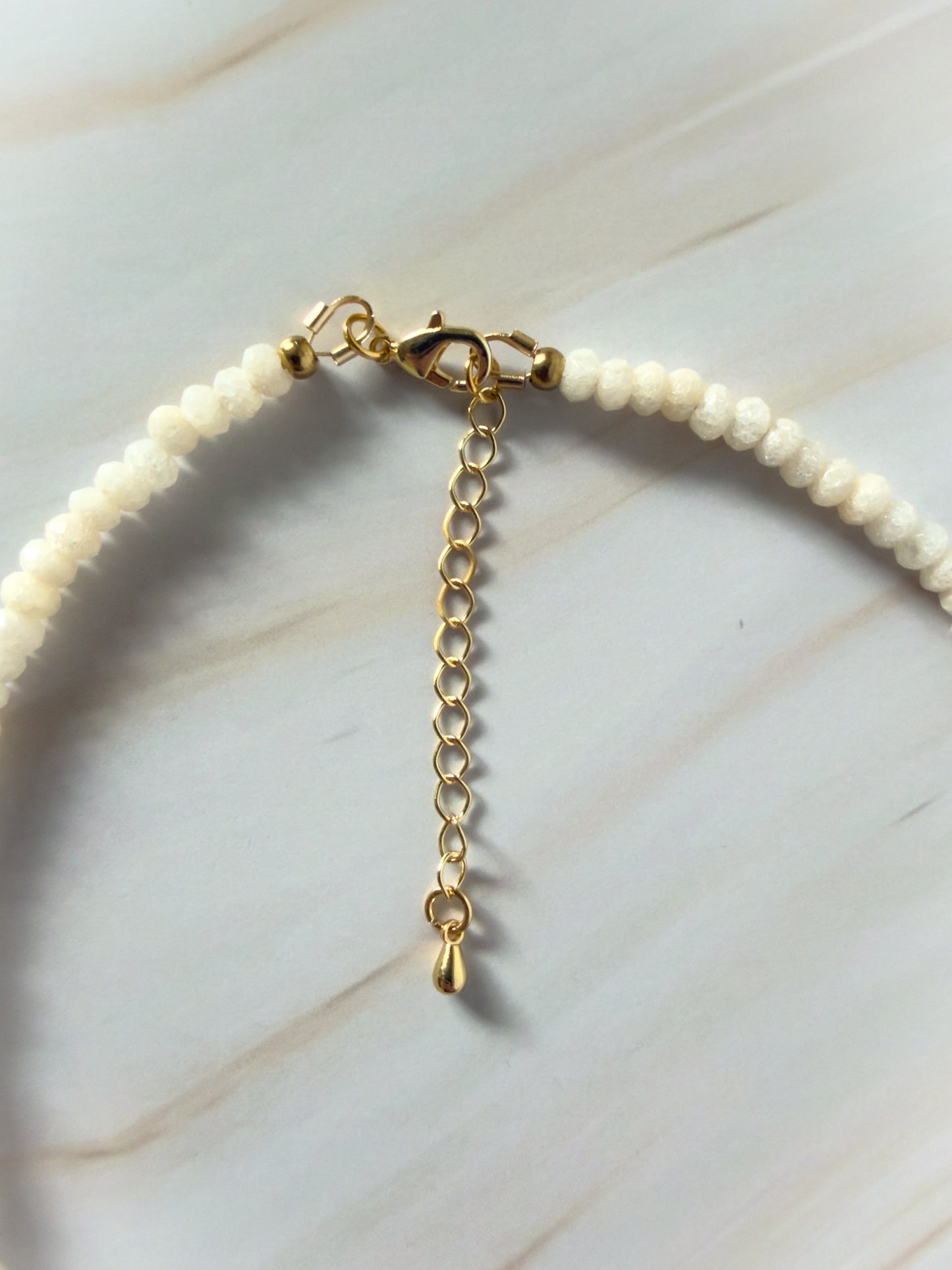 Jade necklace with gold chain extension on a light background