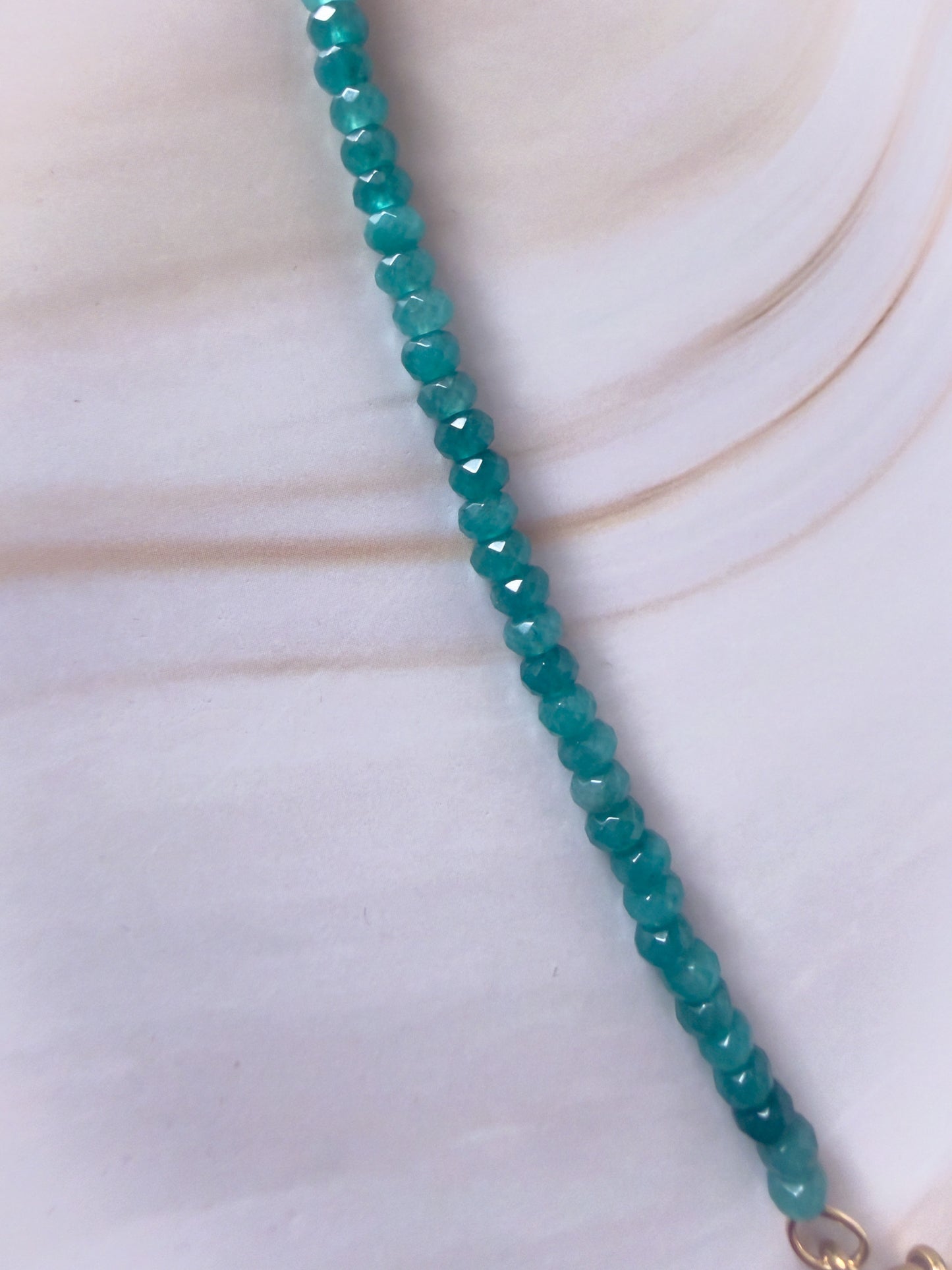 Teal beaded necklace on a light background