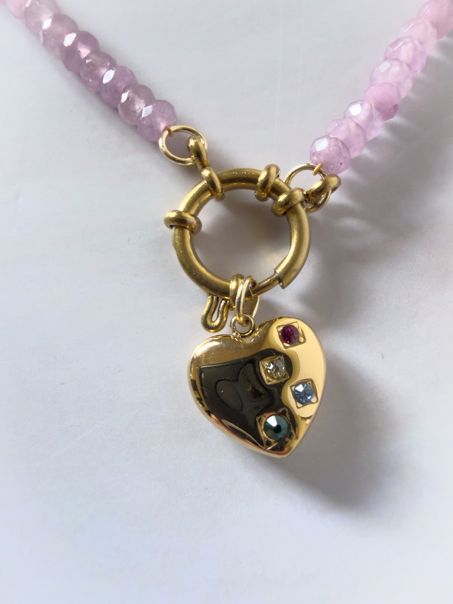 Necklace with a gold heart-shaped pendant featuring embedded stones on a lavender purple beaded chain.