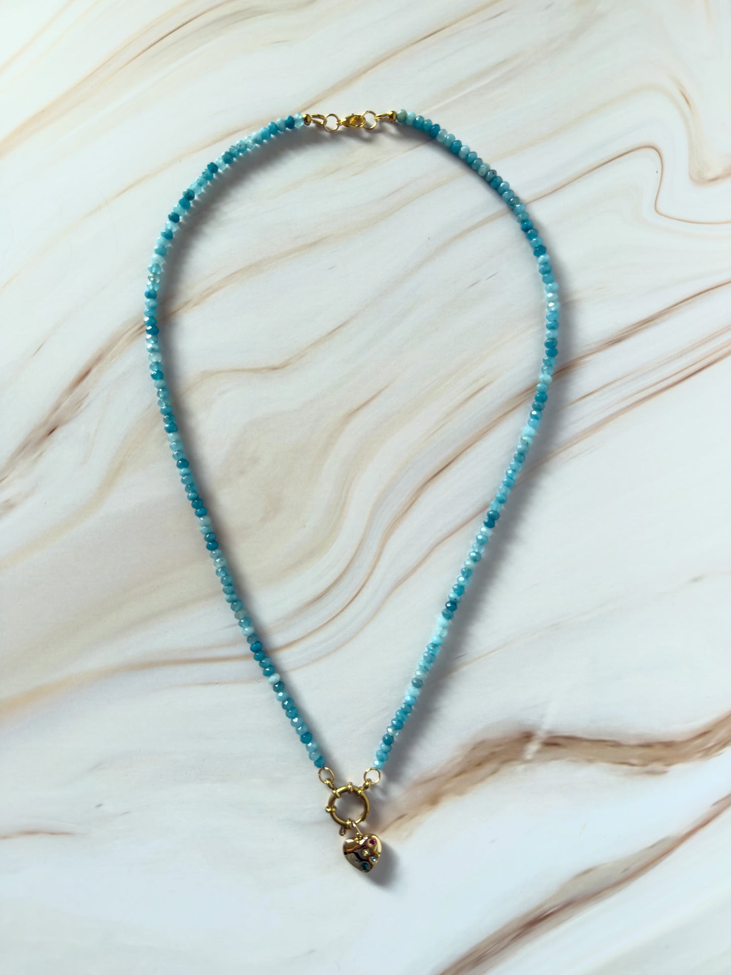 Blue beaded necklace with a gold clasp on a marble surface