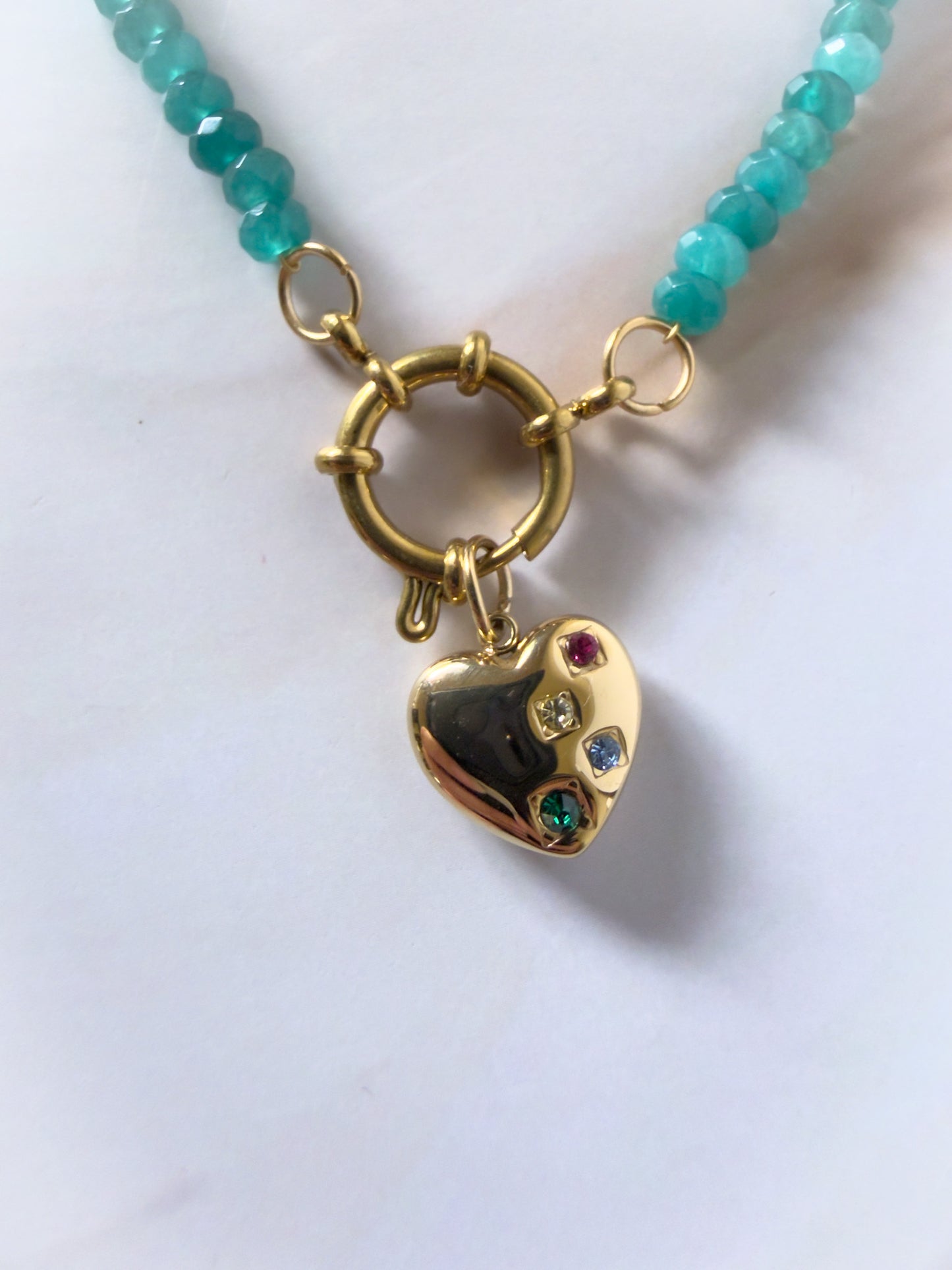 Necklace with a gold heart pendant featuring colored stones on a white background