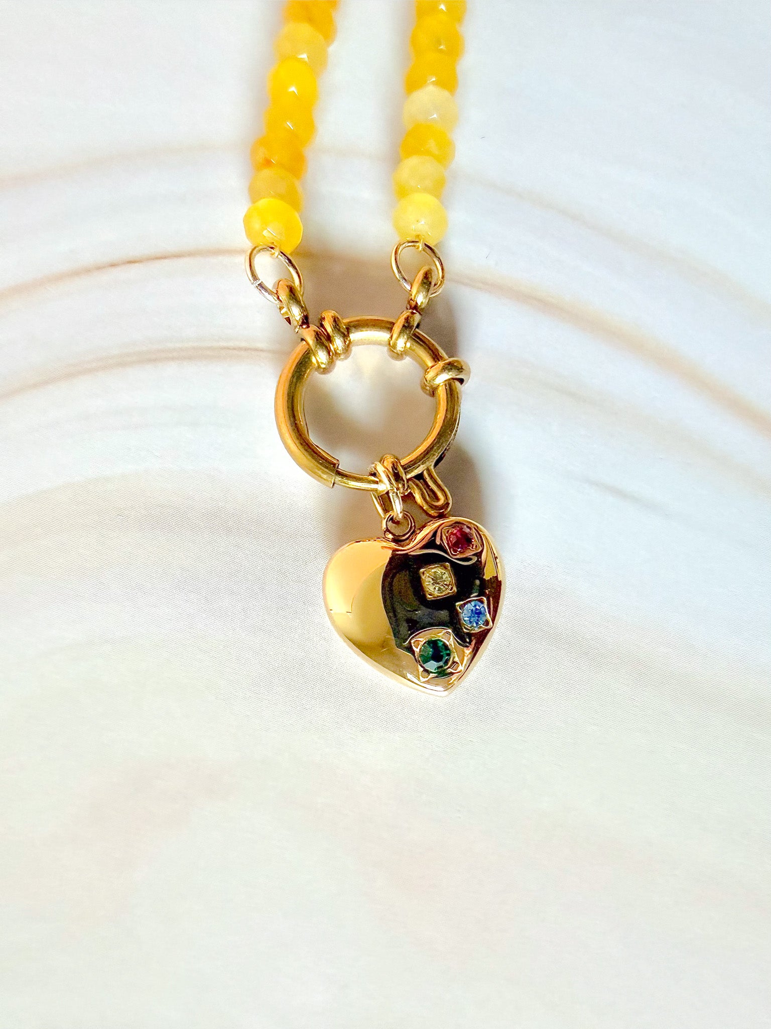 Necklace with a heart-shaped pendant featuring colorful stones on a white background