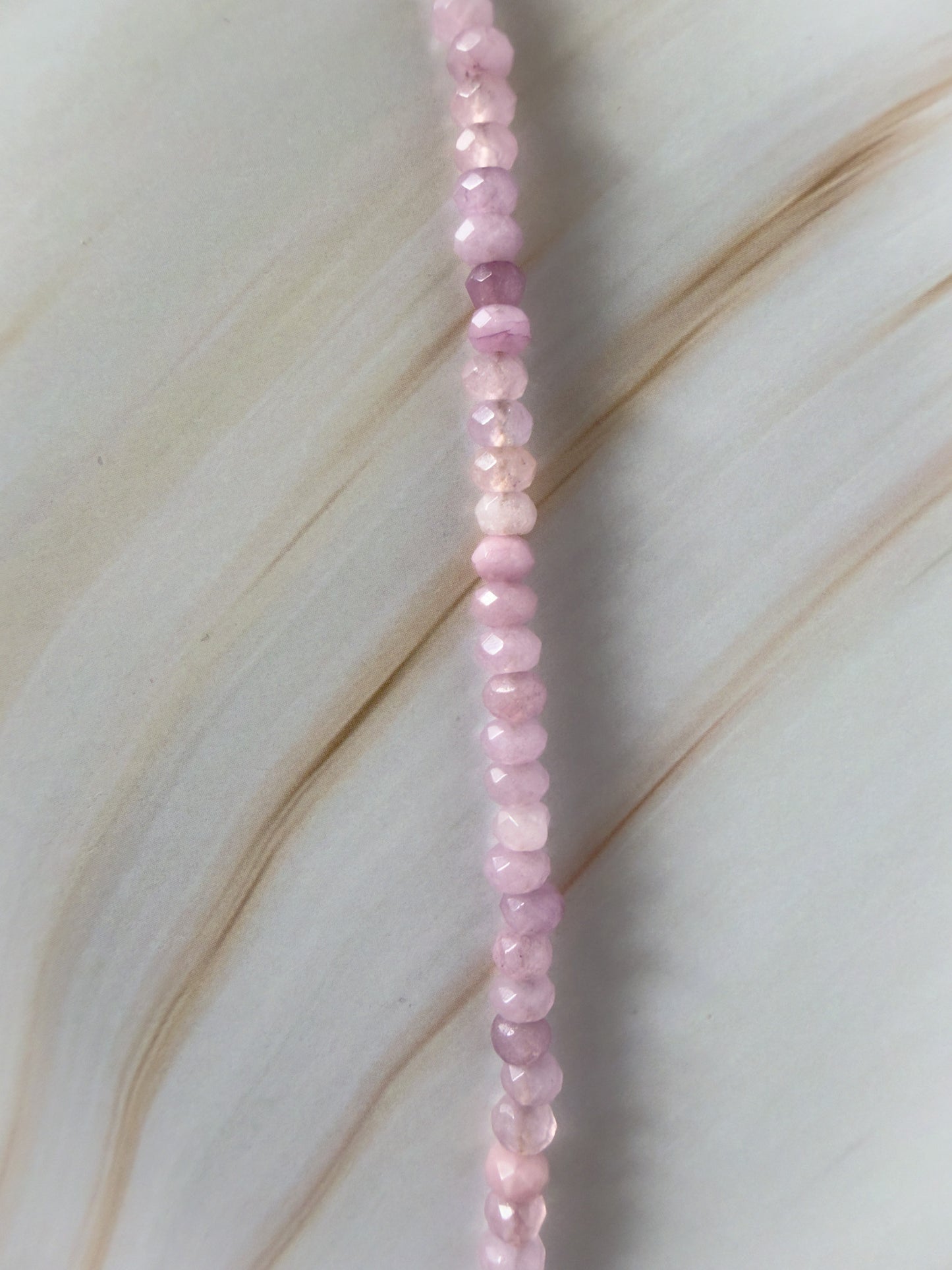 Necklace with pink beads on a light wooden surface