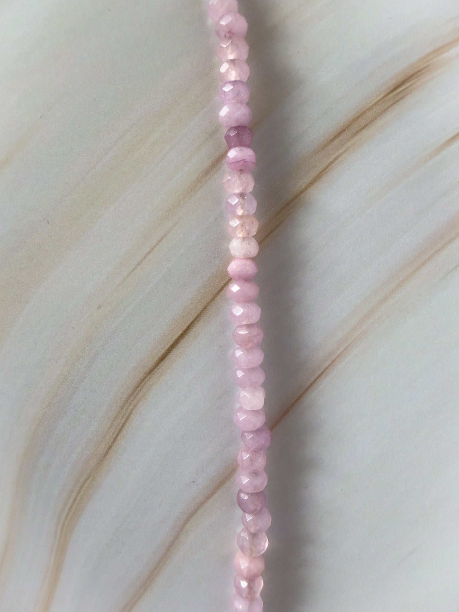 Necklace with pink beads on a light wooden surface