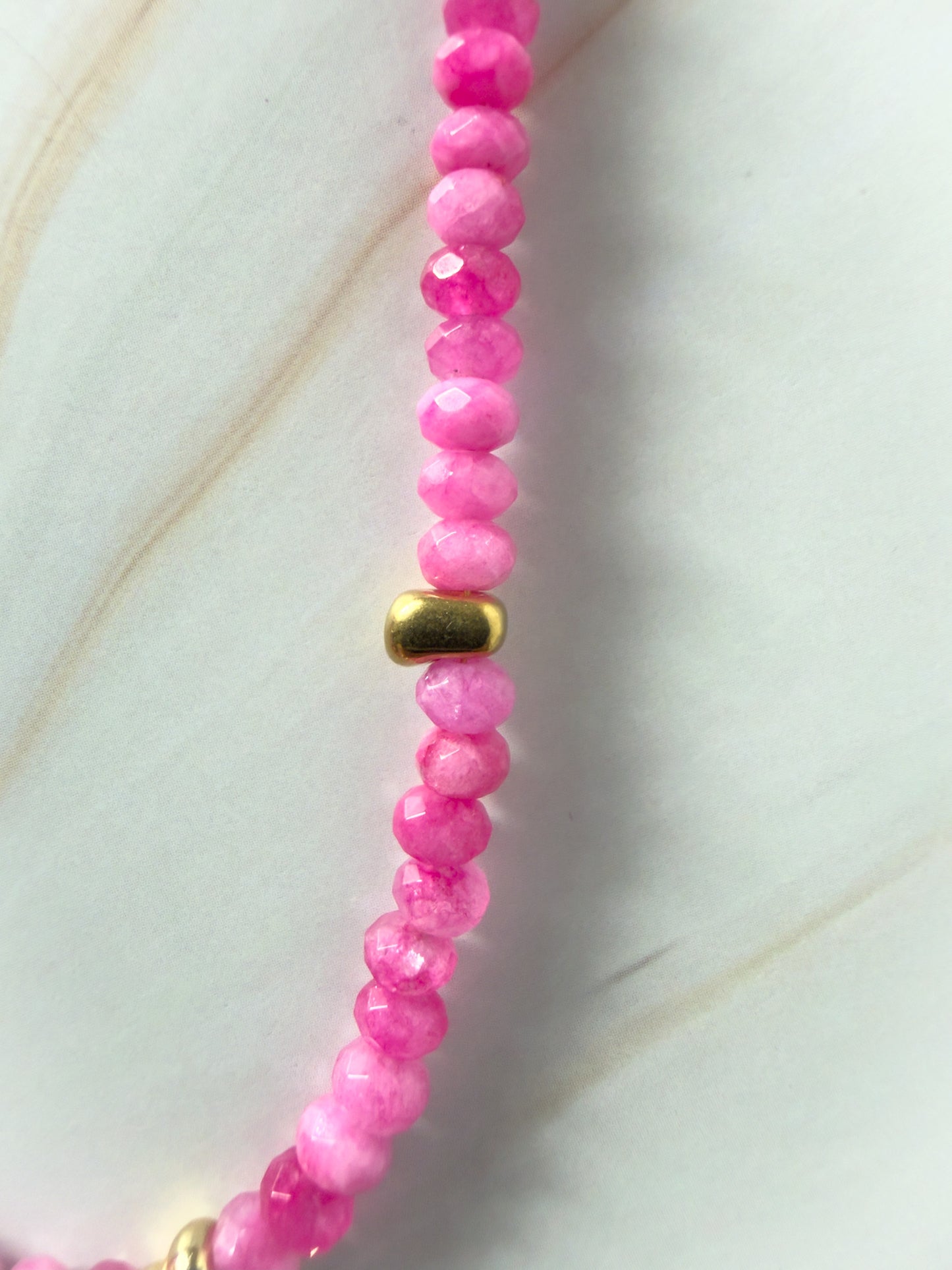 Pink beaded necklace with a gold clasp on a light background