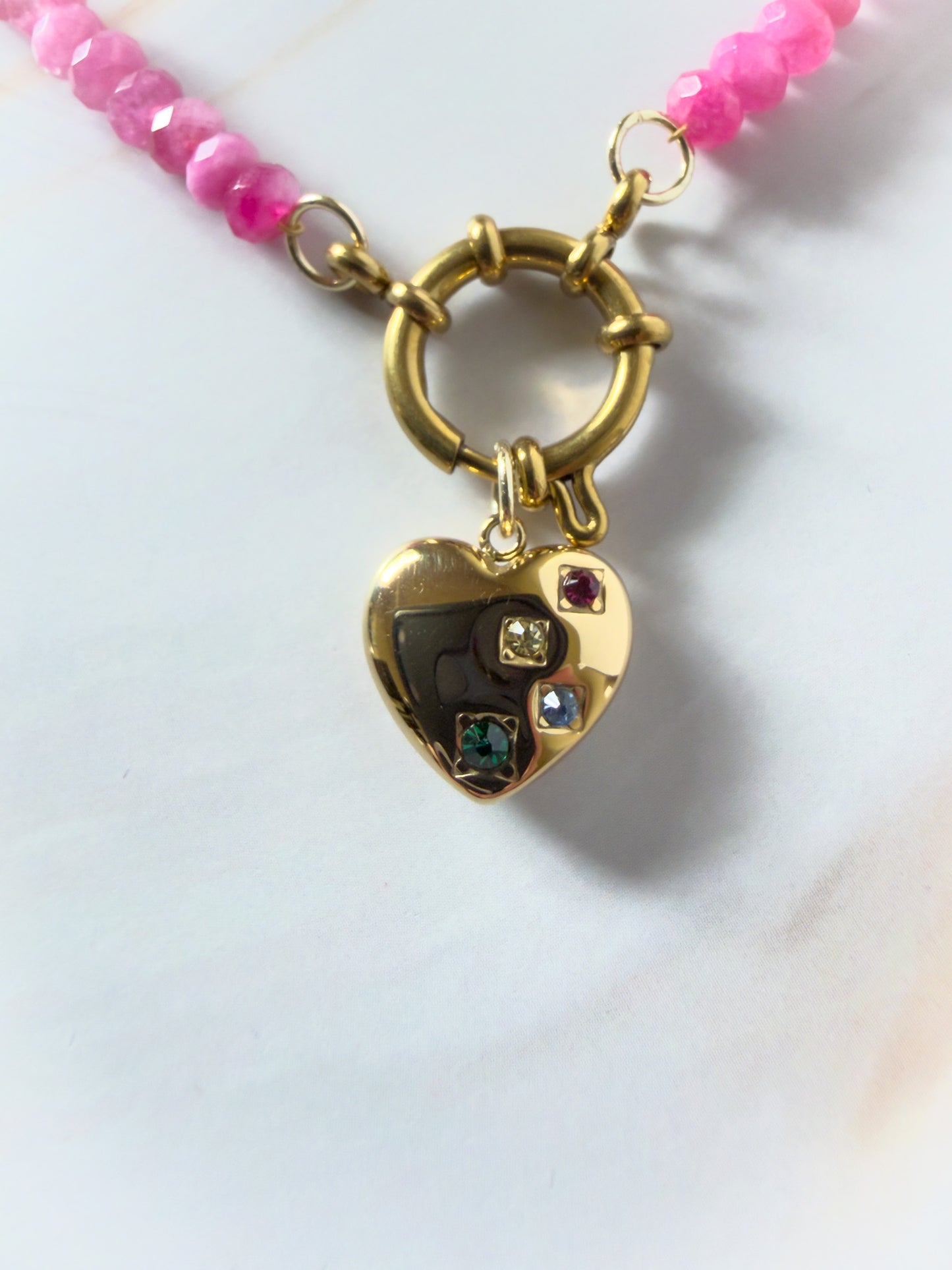 Necklace with a gold heart-shaped pendant featuring colored stones on a white background