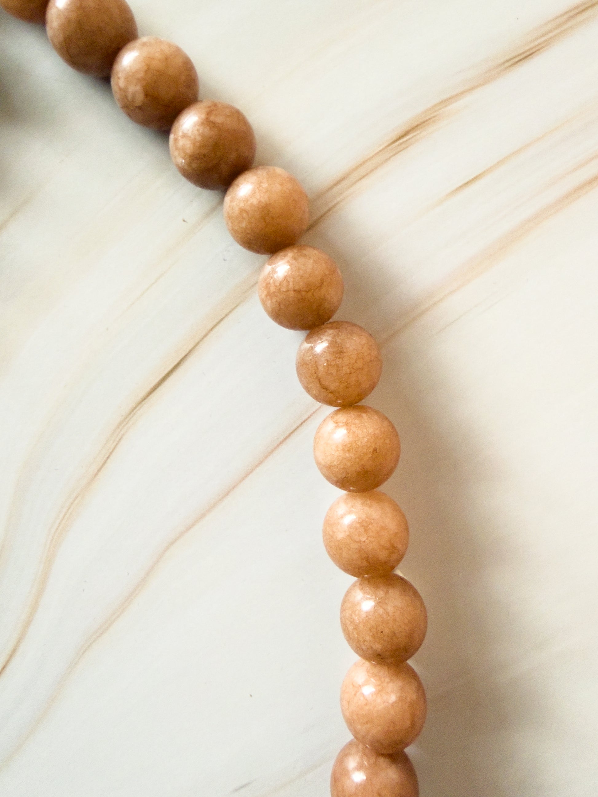 Close-up of a string of peach stone beads on a light background