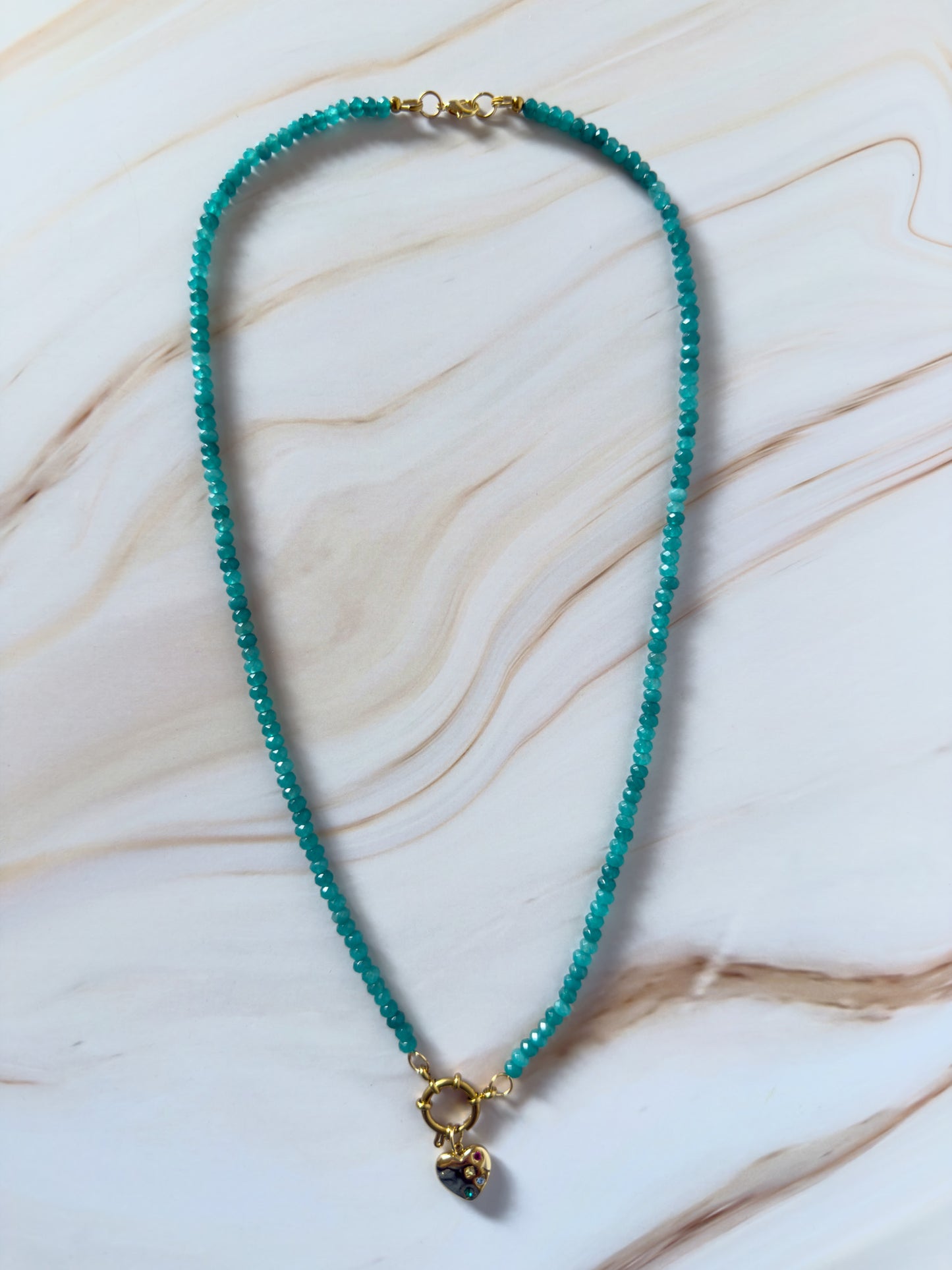 Turquoise beaded necklace with a gold clasp on a marble surface